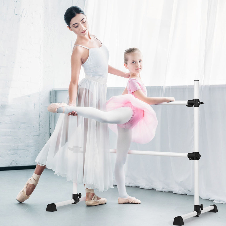 Child stretching on freestanding white ballet barre in studio