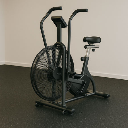 Stationary air bike on speckled rubber flooring in a minimalist gym space.