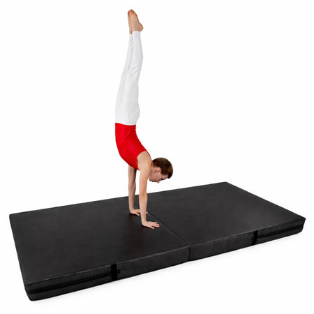 Male gymnast performing a handstand on a black folding crash mat, high-impact gymnastics safety mat by Cannons UK
