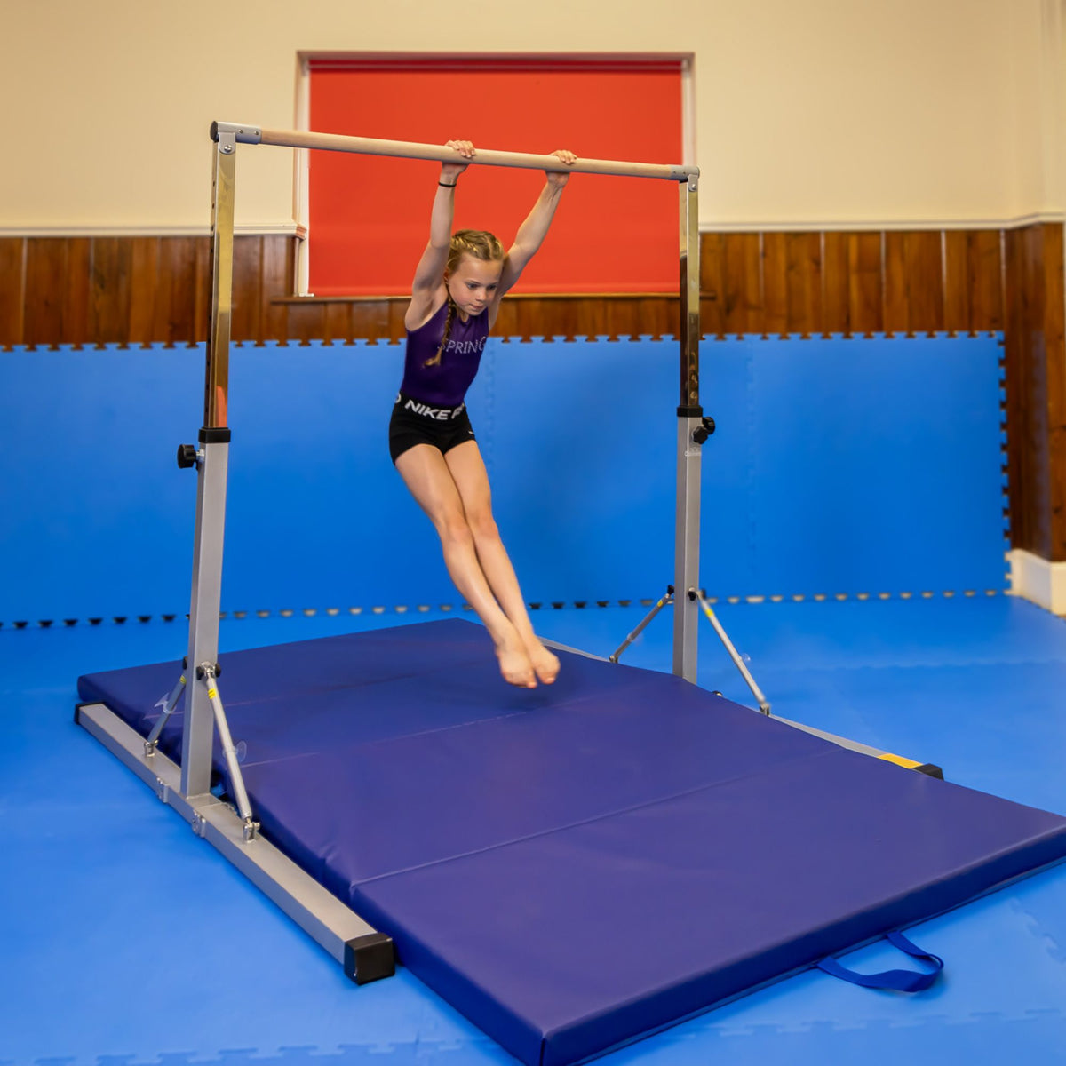 Lifestyle: dismount on pink junior bar — action shot for skills practice with safety matting
