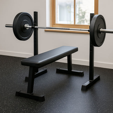 Weight bench with barbell on speckled rubber gym flooring in a modern fitness room