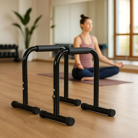 Parallel bars in a boutique fitness studio with a person doing yoga in the background.