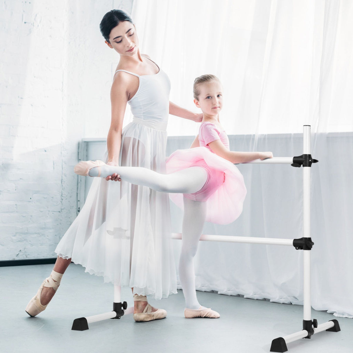 Child stretching on freestanding white ballet barre in studio  

