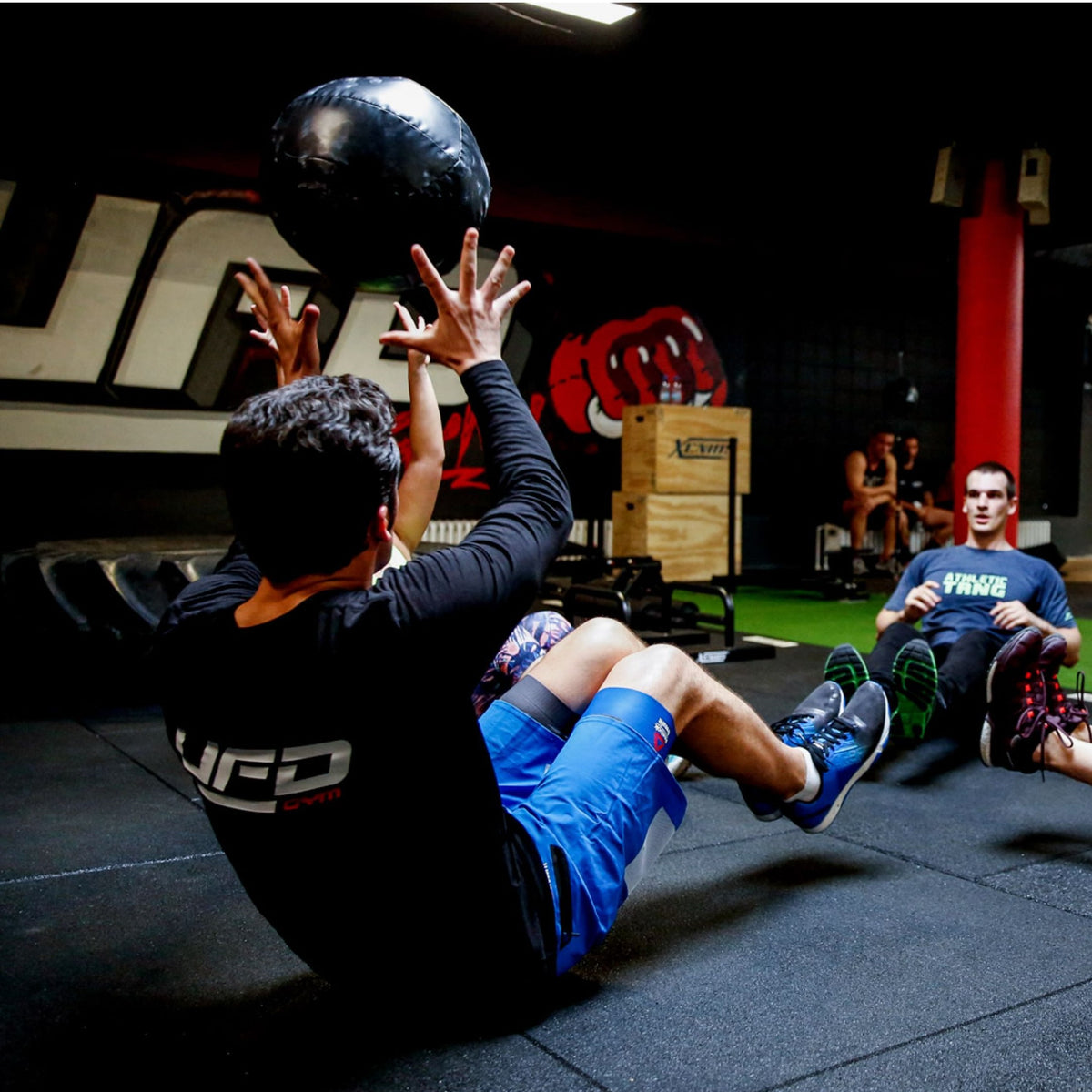 Athletes training on Flatline Pro 30mm tiles — class scene with medicine ball throws; shock absorption and anti-slip surface